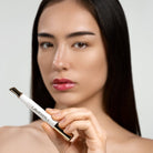 Model holding Lavertu Renewal Adaptive Lip Oil pen with natural glossy pink lips.